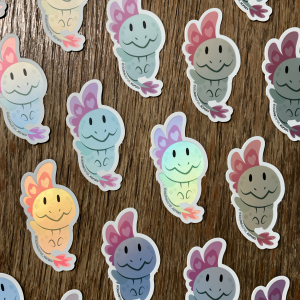 Naklejki przedstawiają uroczego smoka tęczowego z wielką głową i wachlarzem z różowymi serduszkami. Naklejki mienią się delikatnie, matowo.