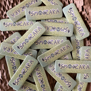 Zdjęcie przestawia rozrzucone w nieładzie przypinki z napisem "smoczara".