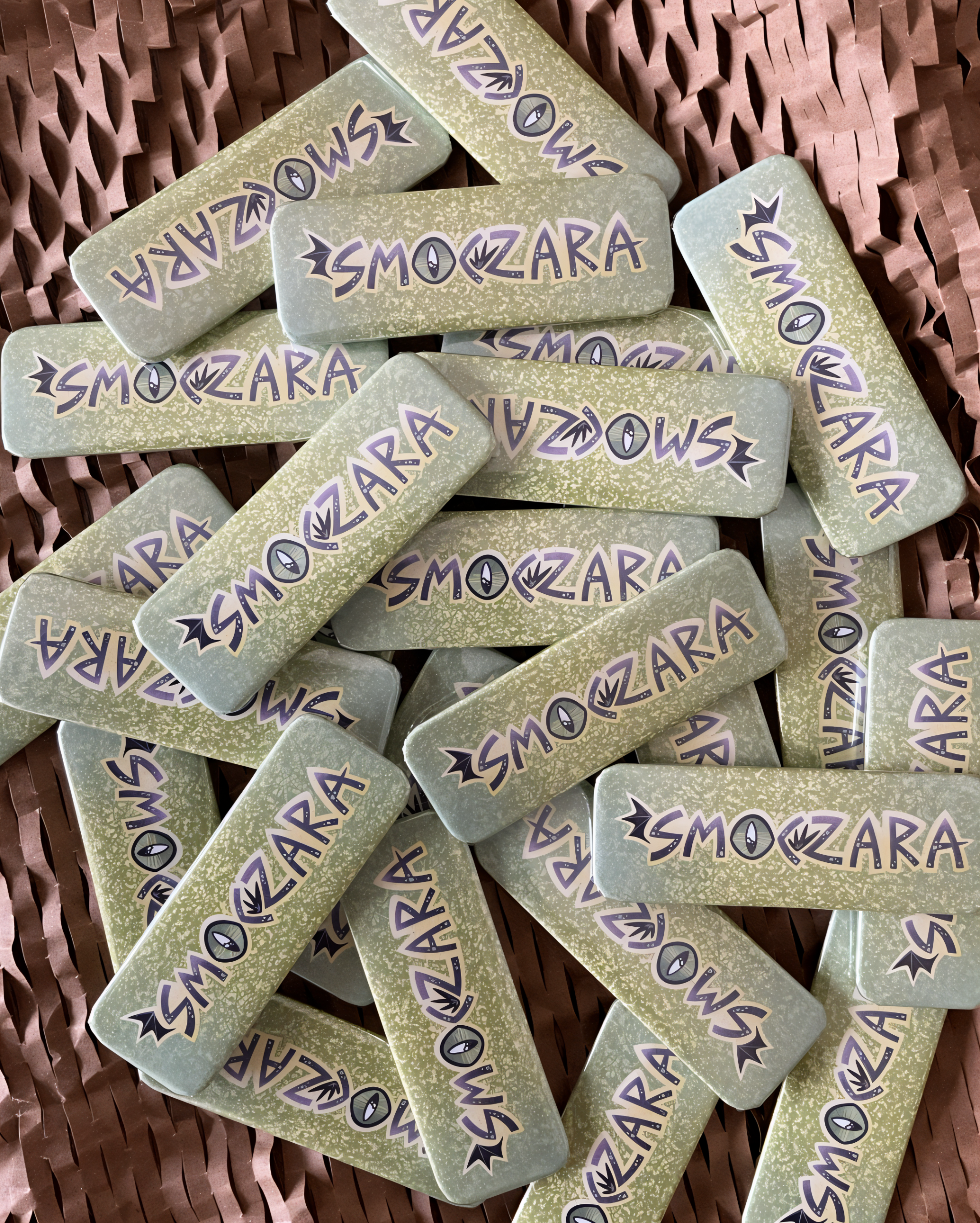 Zdjęcie przestawia rozrzucone w nieładzie przypinki z napisem "smoczara".